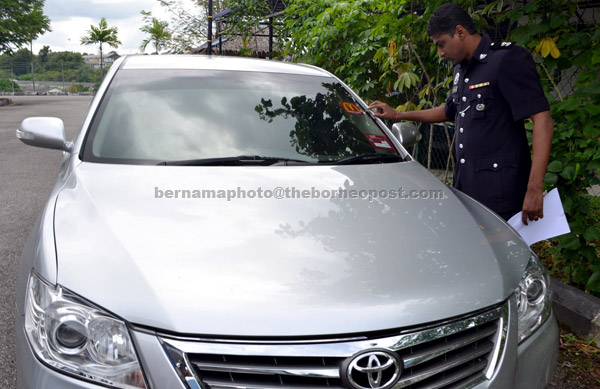 STOLEN CAR:  Investigator R Manimannen examines a car seized after police crippled the ‘Ayie’ gang at a luxury hotel at Banda Hilir. — Bernama photo