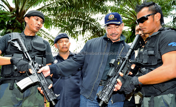 WELL-EQUIPPED: Hishammuddin taking a closer look at the weapons used by General Operations Force members guarding Kampung Tandou in Lahad Datu. — Bernama photo