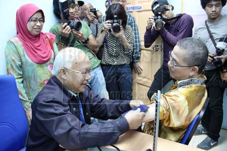 PERIKSA KESIHATAN: Penolong Pegawai Perubatan Klinik 1Malaysia Taman Malihah George Mentai melakukan pemeriksaan kesihatan ke atas Fadillah (kanan) sambil disaksikan oleh Dr Rohani.