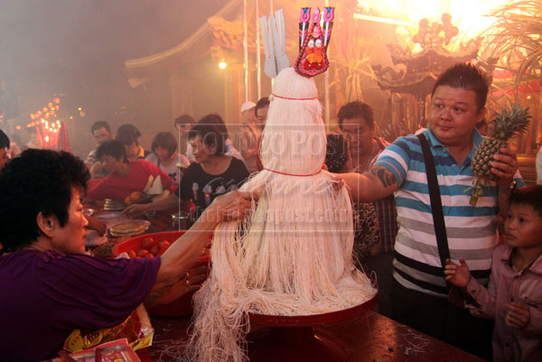 FOR LUCK: Devotees take longevity noodles and fruits.