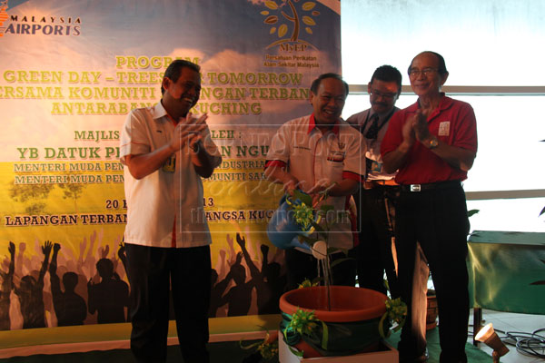 MORE GREENERY: Nansian (centre) watering a tree sapling symbolically to mark the launch of the programme at the airport, accompanied by Sunif (left) and Faizal (right). 
