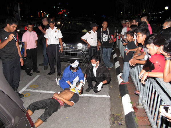 HIT-AND-RUN: A crowd watches as paramedics attend to the injured foreigner following the incident.