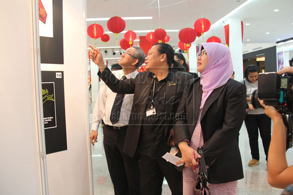 EXCITING: (From left) Sim, Petrus and Rosita admiring a T-shirt design and chat during their tour of the exhibition.