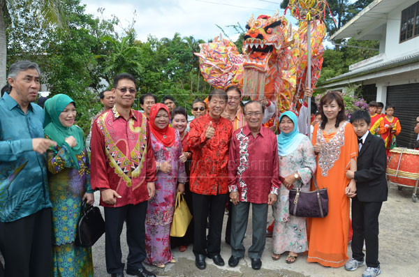 GOOD YEAR AHEAD: Salahuddin (fourth right), Norkiah (third right), Ting (fifth right), Julaihi (third left) and Ting’s wife (second right) pose with a ‘lion’ at the background.