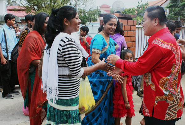 POPULAR MAN: Yong (right) receives Chinese New Year greetings from visitors from the Indian community in Kuching at his Chinese New Year open house on Sunday.