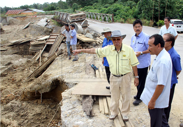 TO BE READY SOON: Manyin pointing at the bridge which is still undergoing construction near the Biawak CIQ Complex. — Photo by Chimon Upon