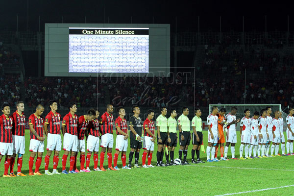 REMEMBER THE FALLEN: Sarawak and Sabah players with match officials observed a minute of silence as a mark of respect for those killed by armed intruders in Sabah. — Photos by Chimon Upon