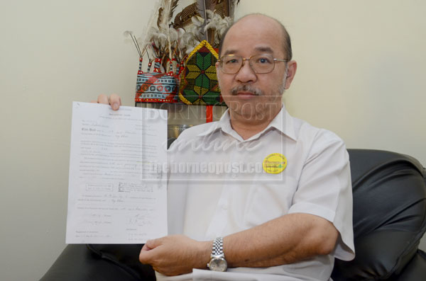 Yong holding a copy of a land title deed which had its 999-year tenure slashed to 99 years, leaving it with only 37 years.