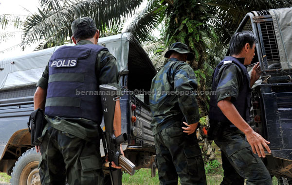 SAD DAY: Malaysian police personnel manning the frontline bringing the bodies of two comrades killed in Kampung Tanduo in Lahad Datu yesterday. The two police commandos were killed during a mortar attack launched by the armed foreign intruders from the Philippines. — Bernama photo