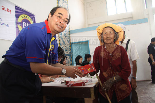 CARING GOVERNMENT: Entri presenting the BR1M 2.0 to the oldest recipient, Puyang Ngau, 107 of Long Teran Kiri in Tinjar.