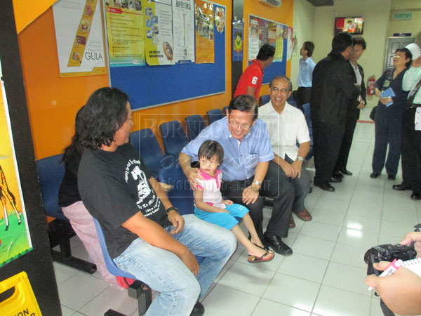 MINGLING WITH THE PEOPLE: Lee (seated second right) chats with a young patient and her parents during his visit to the 1Malaysia Clinic, witnessed by Dr Faizul (seated right).