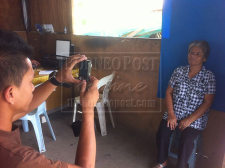 KHIDMAT DIPERLUKAN: Saibi menjalankan perkhidmatan dengan membantu mengisi borang permohonan serta mengambil dan mencetak gambar di dalam gerai yang dibinanya sendiri di pekarangan Kompleks Persekutuan Jalan Simpang Tiga, Kuching. 