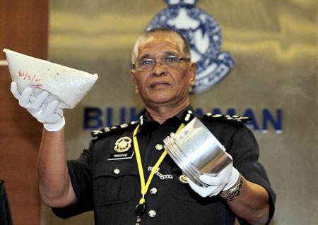 BAHAN BUKTI: Noor Rashid memegang sebahagian dadah jenis heroin yang dimasukkan dalam alat ganti kenderaan setelah tertangkapnya 10 orang warga asing semasa mengadakan sidang media di Ibu Pejabat Polis Bukit Aman di Kuala Lumpur, semalam. — Gambar Bernama