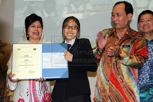 CEMERLANG: Fatimah menyampaikan sijil kepada pelajar cemerlang, Lim Li Ying dari SMK Kuching High sambil disaksikan Abdillah (tiga kiri) pada Majlis Pengumuman Keputusan SPM 2012 di Kuching, semalam. 