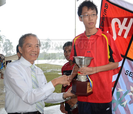 CHAMPIONS THIS TIME: SMK Sacred Heart captain Collymore Tan  receives the overall champion trophy from Sibu Municipal Council chairman Datuk Tiong Thai King.