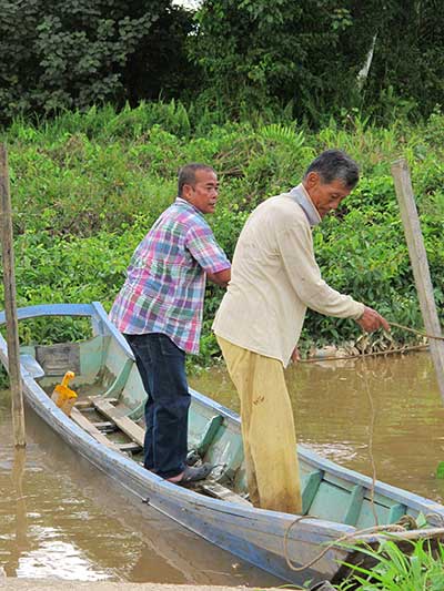 OLD BUDDIES: Two good friends in a boat – Abdillah (left) lending a hand to Mr Ling who is related to pioneer Ling Ching Tu.