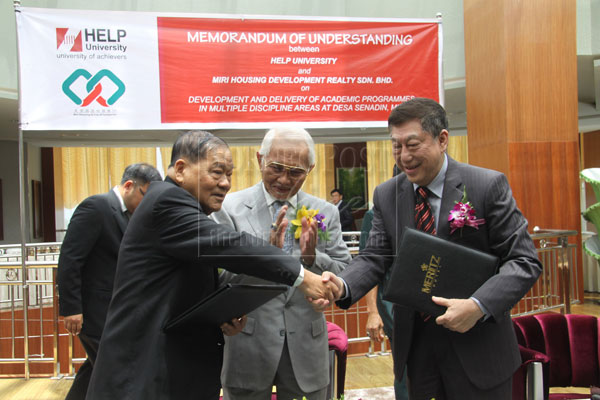 TOWARDS BETTER COLLABORATION: Lau (left) exchanging signed MoU with Paul Chan of HELP University, witnessed by Taib (centre). 