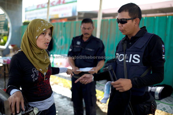 ROUTINE CHECK: Malaysian policemen checking a woman’s documents in Lahad Datu yesterday. – AFP photo