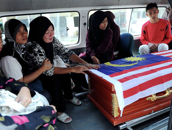 INCONSOLABLE: Siti Banddorah weeps over her husband’s coffin. — Bernama photo