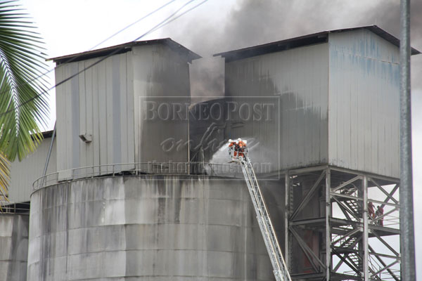 UNDER CONTROL: Fire fighters trying to douse the flames at the cement plant. — Photo by Lai Kui Hong