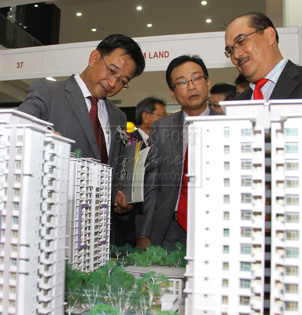 IMPRESSIVE: Abdul Karim (left) takes a closer look at a housing model. Also seen are Zaidi (right) and Sim. — Photo by Chimon Upon