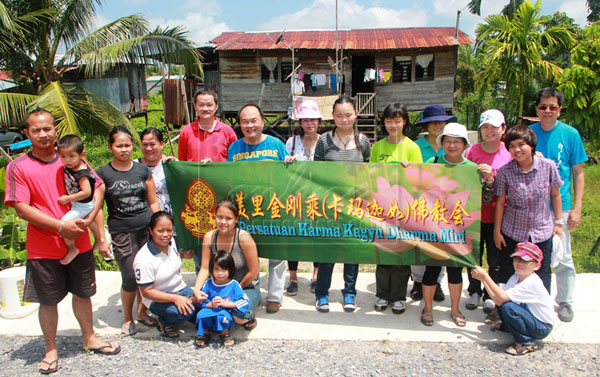 HELPING THE POOR: Goh (second left, behind flag) with his committee and the villagers.