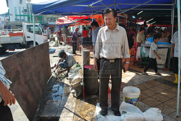 INSPECTION: Chieng checks on the progress to build a drain near ‘tamu’ market to prevent water spilling onto the main road.