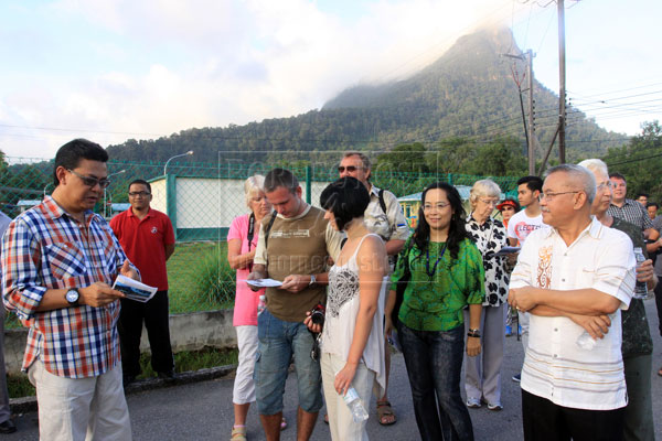 LEISURE WALK: Zulkifli (left) briefing the foreign tourists and invited guests before the start of their ‘Kampung Walk’ at Kampung Santubong. At right is Talip.