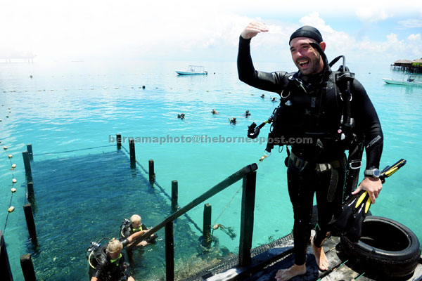 ISLAND IN THE SUN: A tourist appears cheerful after a practice dive at Mabul island near Semporna. The island, famous for its coral reefs and pristine sandy beach, continues to attract visitors from both local and abroad despite the recent intrusion by armed militants in Lahad Datu. — Bernama photo