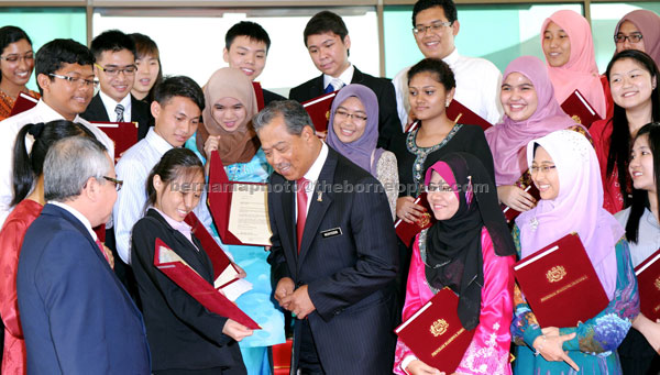 LIGHT MOMENT: Muhyiddin talks to one of the students who received  offer letters for the National Scholarship Programme. — Bernama photo