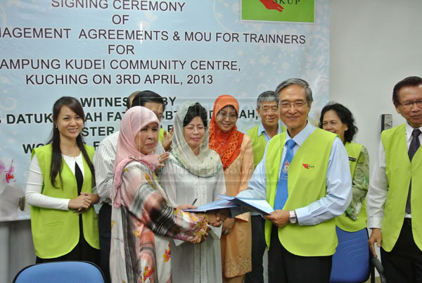 WELL DONE: Rodziah exchanges agreement with Peter Wong after the signing ceremony, witnessed by Fatimah (centre).  