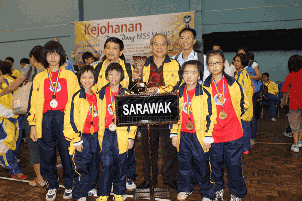 NATIONAL CHAMPIONS:The Girls U-12 team posing with Chong (holding trophy), coach Ling Ching Ang (left, back row) and Sarawak Schools Sports Council table tennis technical chairman Chung Kui Chai (right) at the end of the championship.