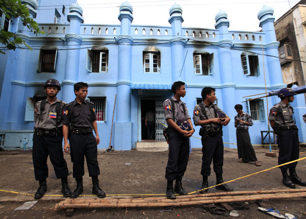 ON GUARD: Police stand in front of a mosque and school dormitory that were damaged in a fire in Yangon. — Reuters photo