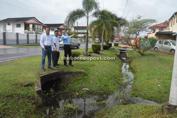 Law (right) inspects the drainage system at Jalan Kropkop 4. Hii is at left.