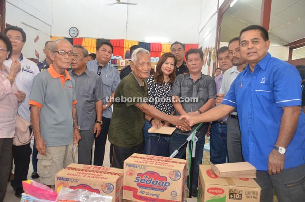 Aaron (right) presents his donation to Tuai Rumah Meruan, as Alexander (fourth right) and others look on. 