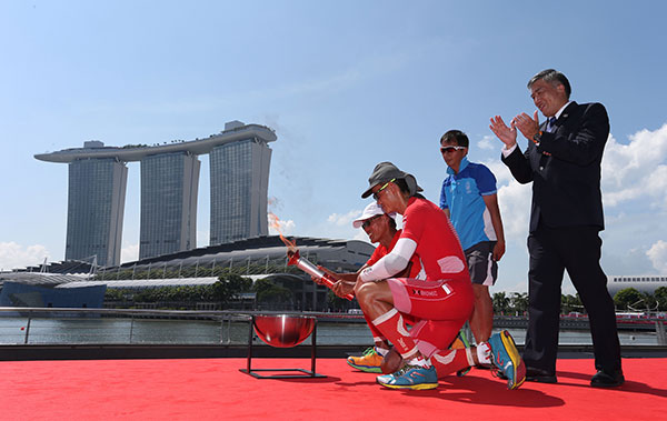 Singapore SEA Games Organising Committee (SINGSOC) exco chairman Lim Teck Yin (right) watches as the flame is lit at the Marina Bay, Singapore. — Reuters photo