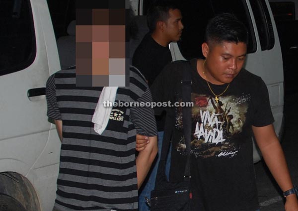 The suspect (left) being led to Miri Central Police Station.