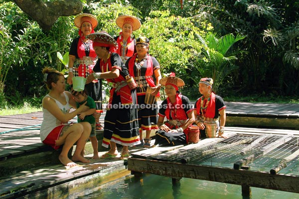Kampung Panchor woman in traditional costumes help bathe a young visitor at the hot spring yesterday. — Photos by Chimon Upon