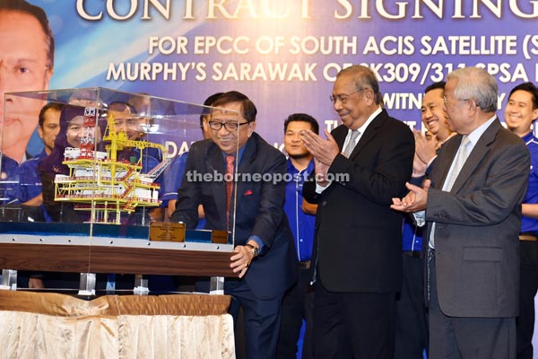 Adenan and Manyin (right) applaud as Abang Abdul Karim unveils a model of Murphy Oil platform after the contract was signed. — Photo by Tan Song Wei 