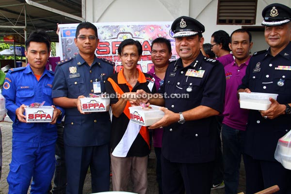 Roslan receives the Bubur Lambuk on behalf of the three departments from SPPA members. — Photo by Chimon Upon