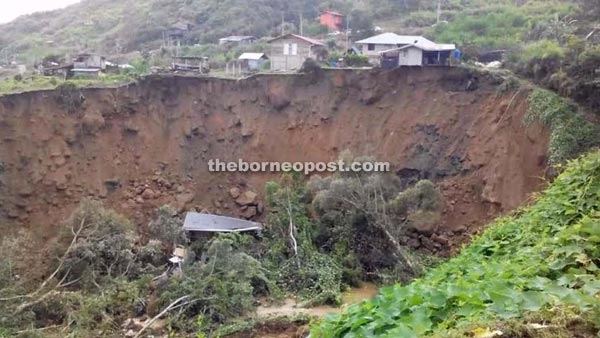 The huge landslide that struck Kampung Mosilou. One house was damaged and several others are perched on the edge of a cliff.