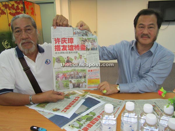 Alias (left) and Hii showing a newspaper clipping of the Bailey bridge launching by the latter in 2013.