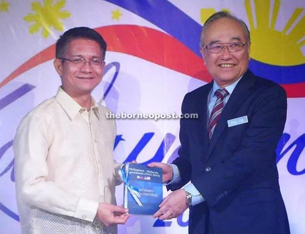 Malaya (left) presents a copy of the book to Minister in the Prime Minister’s Department Senator Datuk Paul Low during its launch in Kuala Lumpur on June 12. 