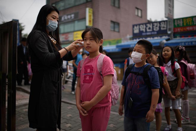 This file photo shows a student has her temperature taken by a teacher outside the Sungshin elementary school in Seoul. South Korea yesterday declared an end to a deadly outbreak of Middle East Respiratory Syndrome (MERS) that killed 36 people, triggered widespread panic and stymied growth in Asia’s fourth-largest economy. — AFP photo