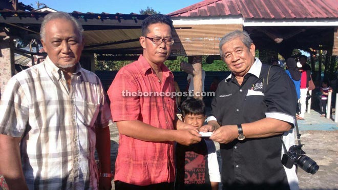 Mazlan (centre) receives a donation from Abang Hashim representing Dr Annuar.