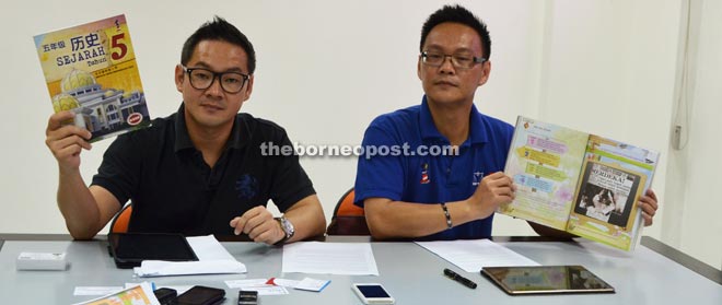 Tiang (left) and Foo holding the Primary 5 History book that MOE needs to rectify with regards to the formation of Malaysia. 