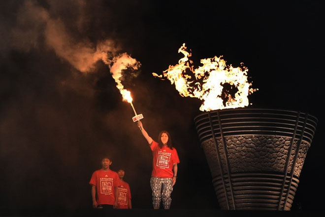 Japan's three-time Olympic women's wrestling gold medalist Saori Yoshida (R) lights a torch during the official farewell event for the national stadium in Tokyo on May 31, 2014. A new national stadium will be built for the forthcoming 2020 Tokyo Olympic games. ©AFP PHOTO / TOSHIFUMI KITAMURA