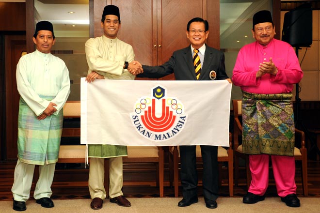 Lee (second right) receives the Sukma flag from Khairy while OCM president Tunku Imran (right) and sports ministry chief secretary Datuk Jamil Salleh look on. — Photo by Lim Chee Sem