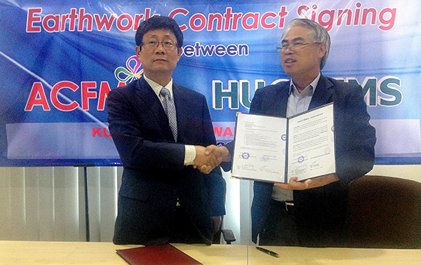 Kim (left) is seen exchanging documents with Charlie (right) after the earthwork contract signing ceremony held here recently. 