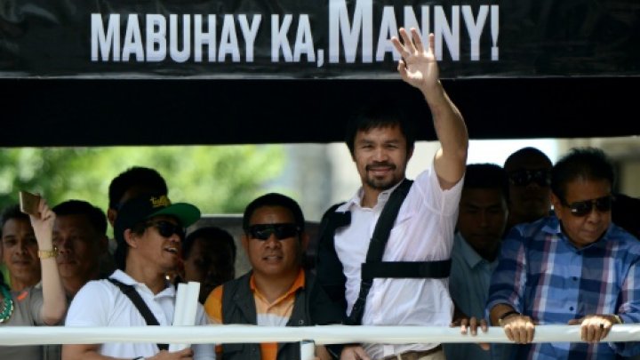 Boxing icon Manny Pacquiao of the Philippines waves to his supporters during a welcome parade in Manila on May 13, 2015 -AFP